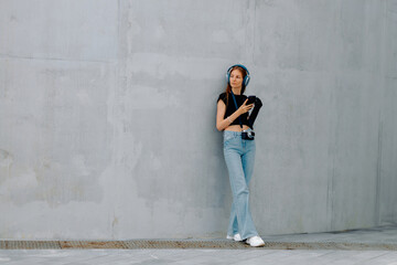 Fototapeta premium Woman with a bionic prosthesis standing against a concrete wall while listening to music