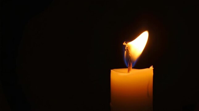 Single Candle Flame Burning Brightly in Deep Darkness for Memorial Vigil or Spiritual Reflection