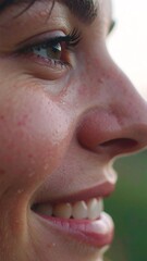 A close-up shot features a person's smiling face profile. The eye gleams, showcasing details of the skin's texture and the curve of the nose