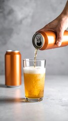 A close-up shot of a beverage being poured from a can into a glass. A second can sits behind the glass