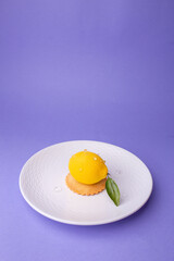 Lemon-shaped dessert on white plate - freshness and elegance against purple