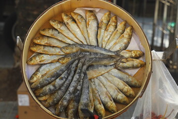 Dried fish arranged in a circular pattern in a wooden container at local market. Traditional preserved seafood rich in protein, symbol of Mediterranean cuisine and authentic street food culture.