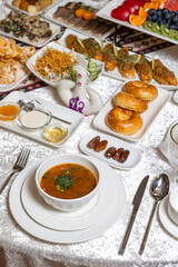 A lavish spread featuring hot soup, golden buns, dates, fresh fruit platter, and assorted savory bites on a crisp white tablecloth. Perfect for catering, hotel promotions, or banquet marketing.