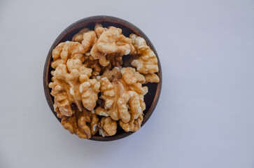 Walnut without shell in wooden bowl on light background