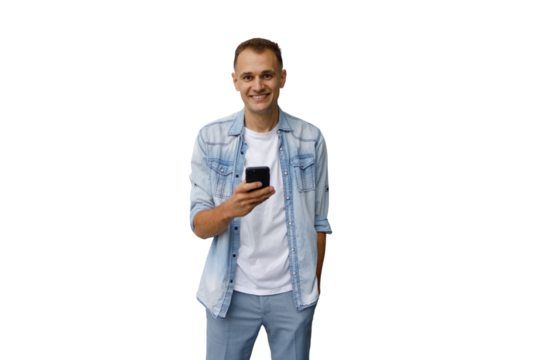 Smiling man standing, holding a smartphone, actively using a mobile application. Transparent background