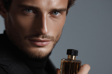 Intense Gaze of a Handsome Man with a Bottle of Cologne
