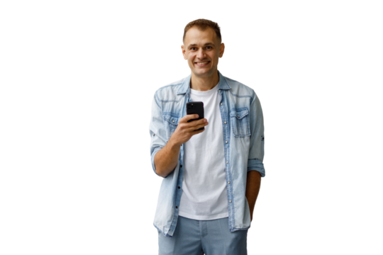 Smiling man wearing casual denim shirt and white t-shirt, holding smartphone, looking at camera, full body on transparent background