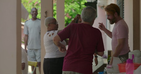 Group of friends raising hands and dancing energetically at an outdoor gathering, celebrating...