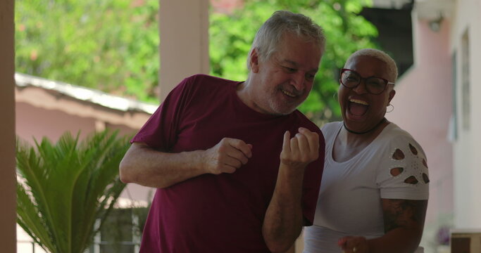 Elderly man and diverse group, including a cheerful Black woman, sharing a joyful dance at a lively outdoor gathering, celebrating inclusion, happiness, and bonding - Powered by Adobe