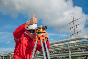 Man engineer using theodolite outdoors and thumbs up