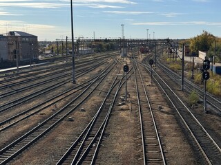 The railway tracks stretch elegantly under the vast expanse of a bright blue sky above