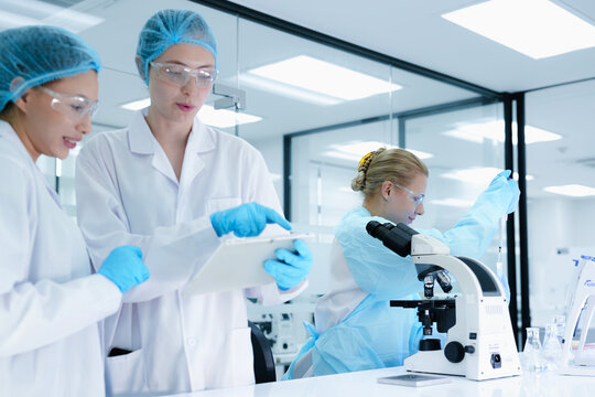 A senior scientist mentors a junior colleague in a modern lab, using a tablet to guide her through a precise pipetting technique, fostering hands-on learning and skill development. - Powered by Adobe