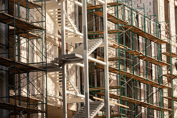 Construction site with scaffolding and staircases during daylight in an urban area, showcasing...