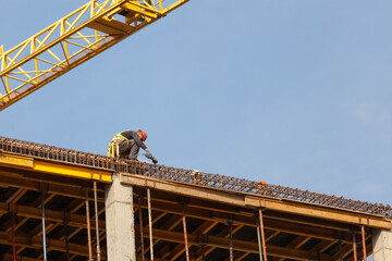 Construction worker on building site during daylight hours executing tasks with safety gear and...