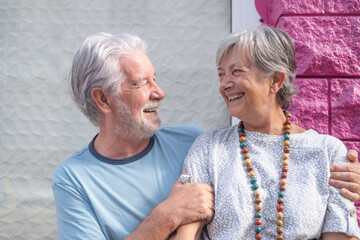 Lovely senior couple hugging smiling sitting in outdoors looking at each other happily. Youthful couple enjoying retirement lifestyle
