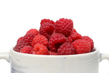 On a white background there is a plate with ripe juicy raspberries.	