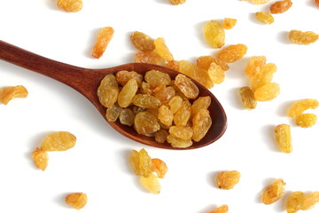 Yellow raisins lie on a wooden spoon on a black background.	