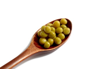 On a white background lies a wooden spoon with canned green peas.	