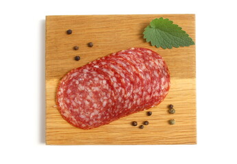 There are round pieces of salami on a wooden board.	