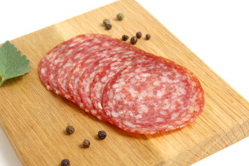 There are round pieces of salami on a wooden board.	