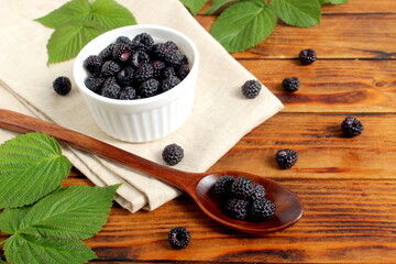 There is a blackberry berry in a bowl on a wooden table.	