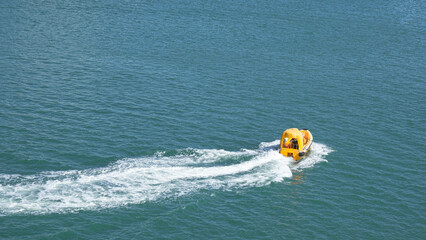 Bright yellow watercraft gliding across tranquil blue waters, leaving a white wake behind,...