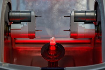 A dental milling machine with red backlight and a finished ceramic crown