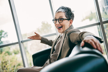 Obraz premium Confident mature businesswoman enjoying a light moment in a modern office setting emphasizing positivity
