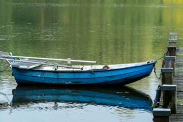 Obraz premium Blue rowing boat moored at rustic dock