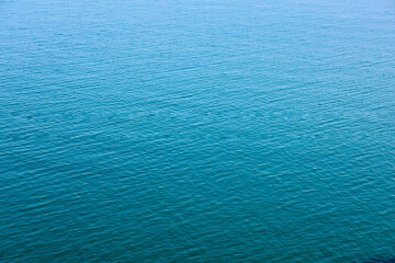 Obraz premium Water Surface Texture. Beautiful Blue Waves. Global Warming. Water texture. View of a lake surface texture. Seascape from top perspective. Close Up waves. Turquoise sea water. Sea water in low tide.