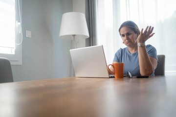 Stressed woman working from home on laptop looking confused and overworked