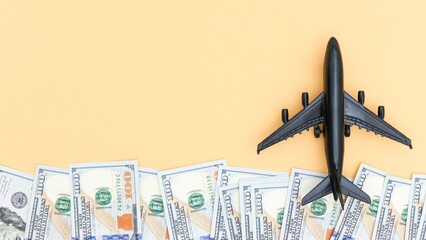 Flight expenses. Airplane over dollars isolated on pastel background. Travel cost concept.