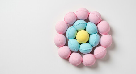 Obraz premium Colorful bath bombs arranged in flower pattern on white background. Spa and self-care beauty products flat lay. Top view with copy space for text