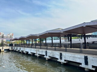 Fototapeta premium Exterior shot of a modern waterfront terminal structure with tiered brown roofing and concrete pillars. Ideal for urban transport, city infrastructure, water travel, or architectural backgrounds