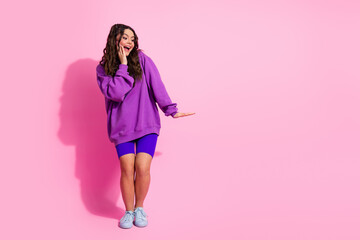 Young fashionable woman in casual activewear posing with happy expression against pink backdrop...