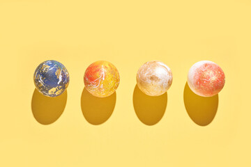 Colorful marbled balls on yellow background with shadows casting patterns.