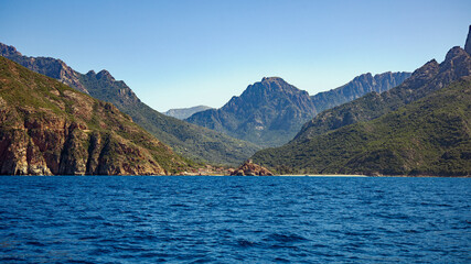view from the sea of the small town of Porto Ota and the coastline with mountain backdrop in sunshine and blue skies