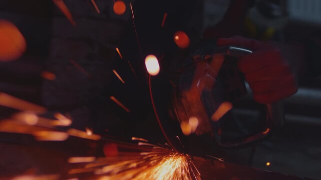 Cutting angle grinder machine cuts metal, chips fly. Close up of spinning disk tool with bright flying sparks in a workshop setting. Detailed macro shot of cutting steel or iron. Industrial factory