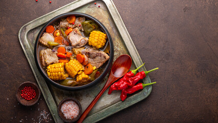 Chilean cuisine of Latin America. Traditional Chilean cazuela de cerdo. Pork soup with potatoes and corn, stew with corn, chili and carrots on dark background top view