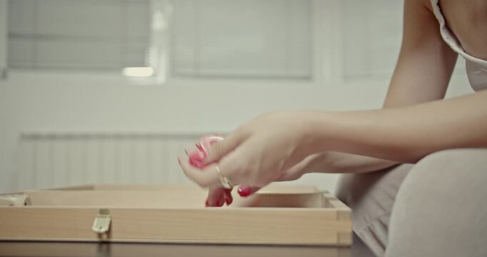 Watch a close-up of a woman's hands as she skillfully manipulates red backgammon checkers. This video highlights the tactile and auditory experience of playing a classic board game.