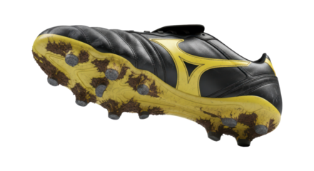 Black and yellow soccer cleat with muddy studs on transparent background