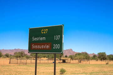 Green road sign for Sesriem and Sossusvlei in Namibia. Distance sign on the C27 highway. Seen during a tour of Namibia, Africa.