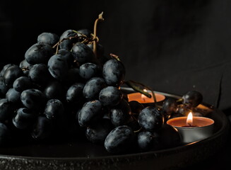 Dark grapes with a lit candle - Romantic and Cozy Autumn Scene with Grapes and Candlelight
