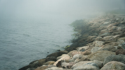 Dense Fog Rolling Over a Rocky Seashore Breakwater
