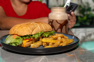 Close-up of fast food meal with sandwich, fries, and chocolate milkshake on table