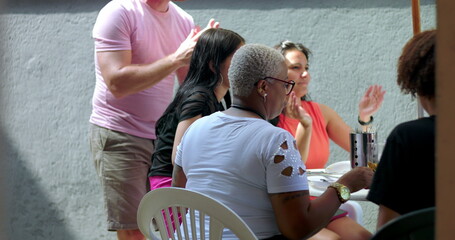 Group of diverse individuals gathered at an outdoor table, engaged in conversation and interaction,...