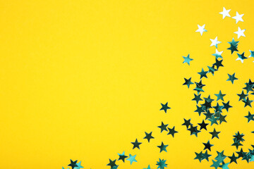 Blue glitter stars on yellow background. Space for text