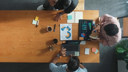 Top view of skilled project manager talking about financial graph to investors while sitting at meeting table with data analysis document. Diverse team discussing and brainstorming idea. Convocation.