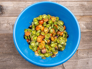 Sliced ​​cherry tomatoes of bright colors - fresh and juicy in a blue bowl, top view.
