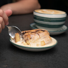Chocolate dessert on plate served with hand holding fork.